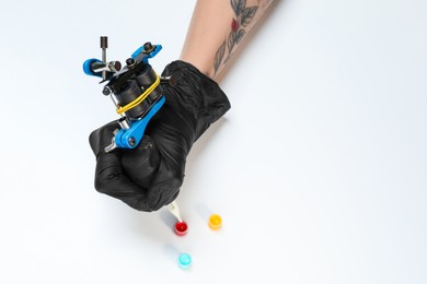 Tattoo artist with professional machine and colorful ink on white background, closeup