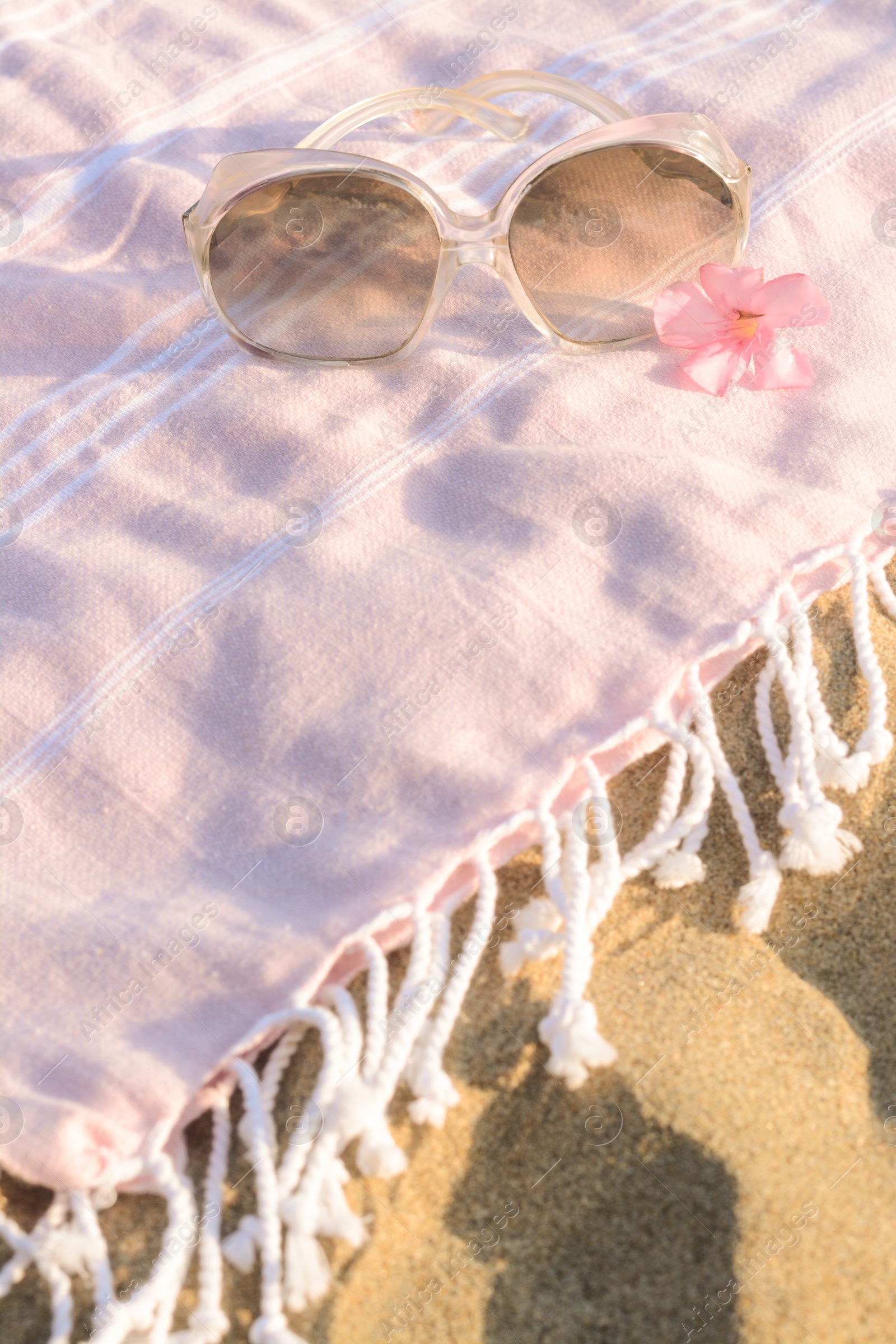 Photo of Beautiful sunglasses with tropical flower on pink blanket