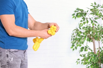 Man making balloon figure on blurred background, closeup. Space for text