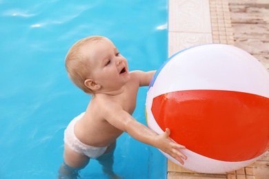 Photo of Little baby playing with inflatable ball in outdoor swimming pool. Dangerous situation
