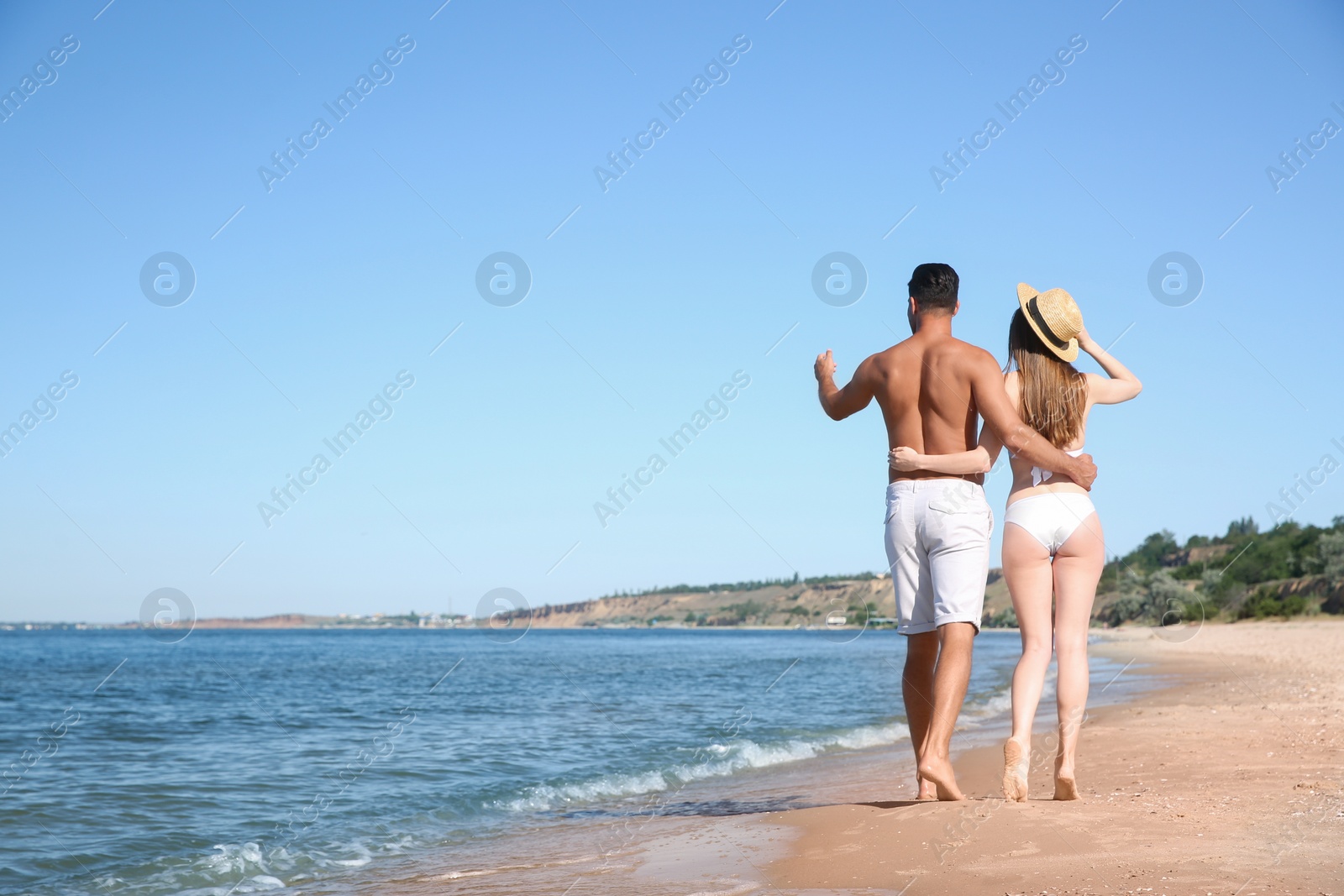 Photo of Woman in bikini and her boyfriend on beach, back view with space for text. Lovely couple