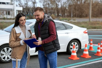 Young woman with instructor near car at driving school test track