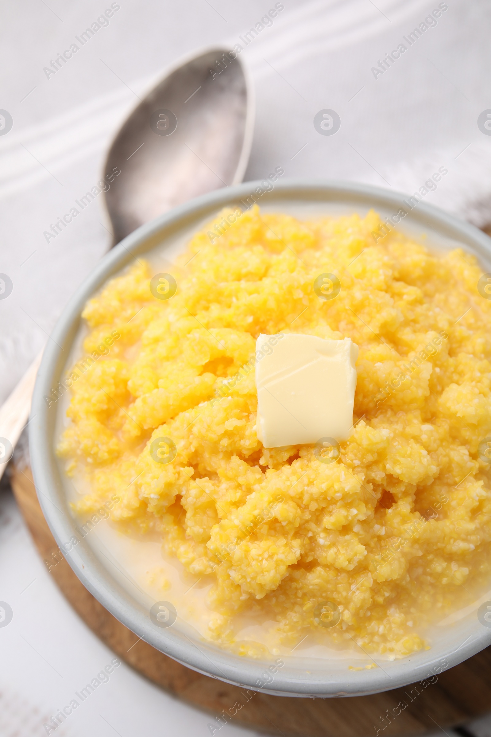 Photo of Tasty cornmeal with butter in bowl served on table, above view