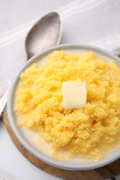 Photo of Tasty cornmeal with butter in bowl served on table, above view