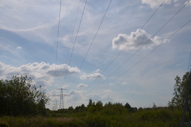 Photo of Modern high voltage towers in field on sunny day