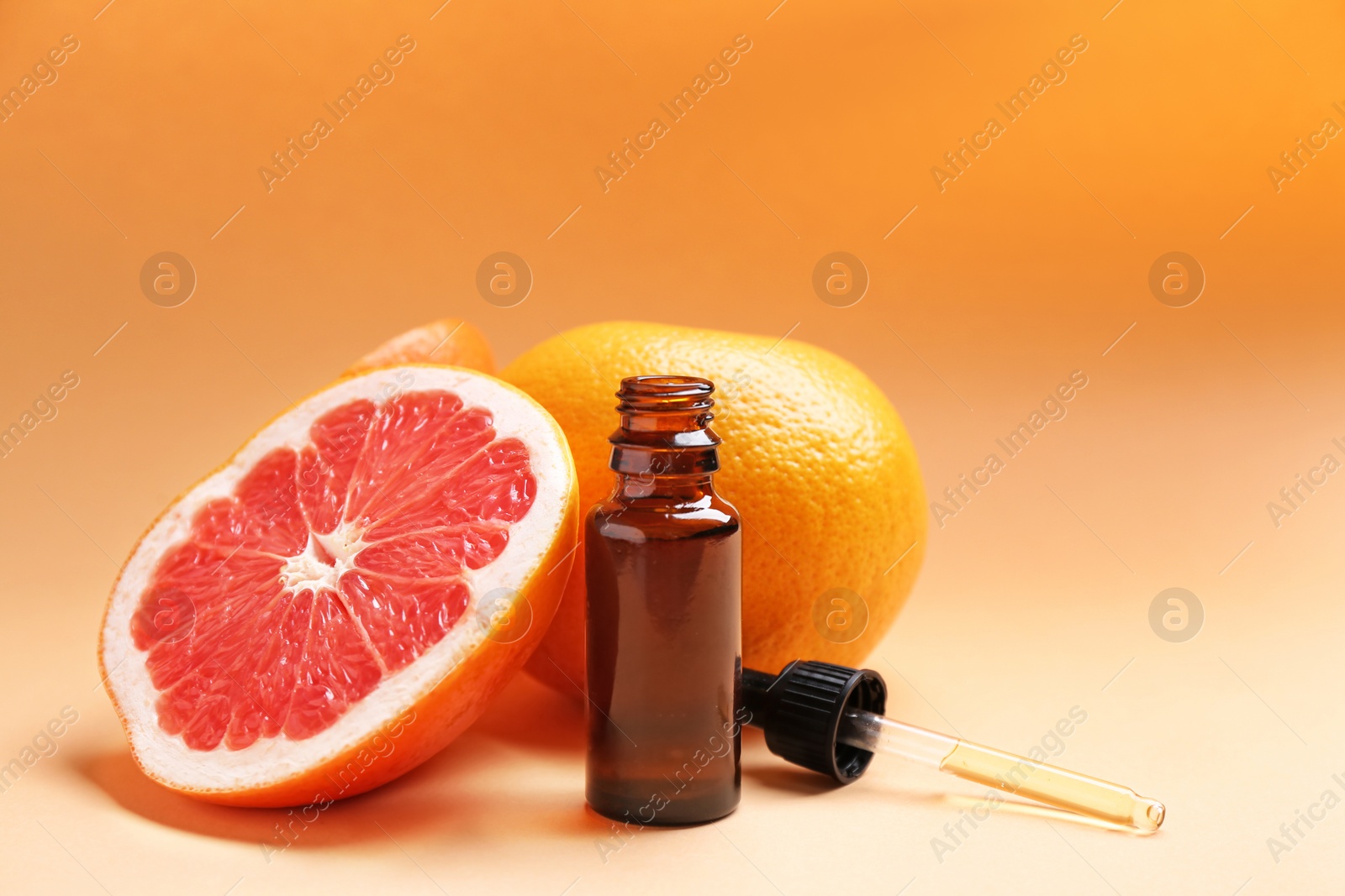 Photo of Bottle of essential oil and fresh grapefruits on color background