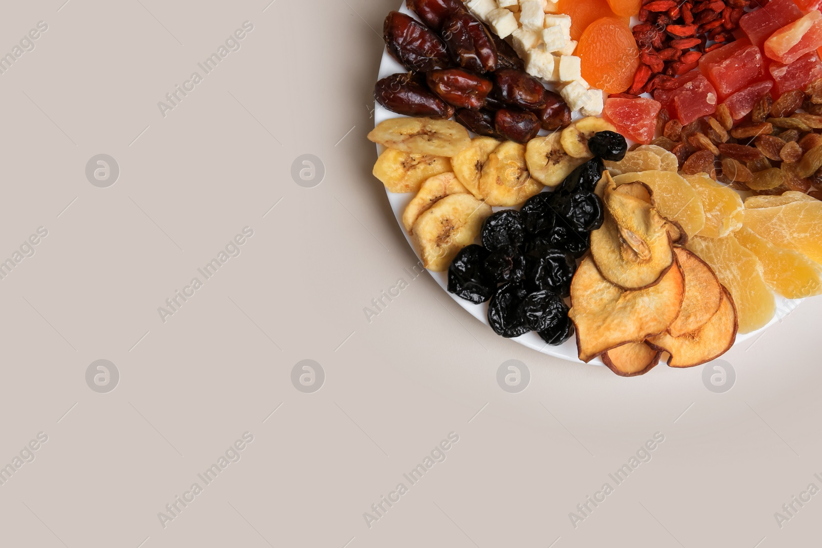 Photo of Plate with different dried fruits on white background, top view. Space for text