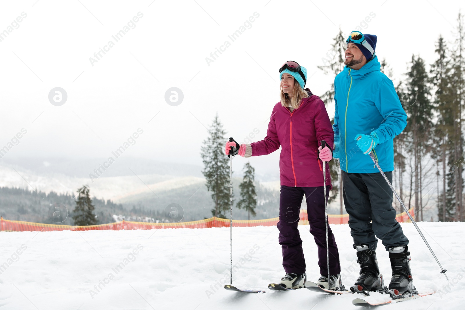 Photo of Couple of skiers on slope at resort, space for text. Winter vacation