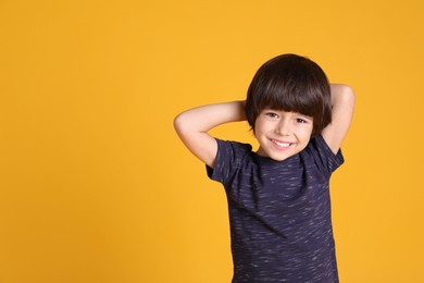 Photo of Portrait of cute little boy on yellow background, space for text