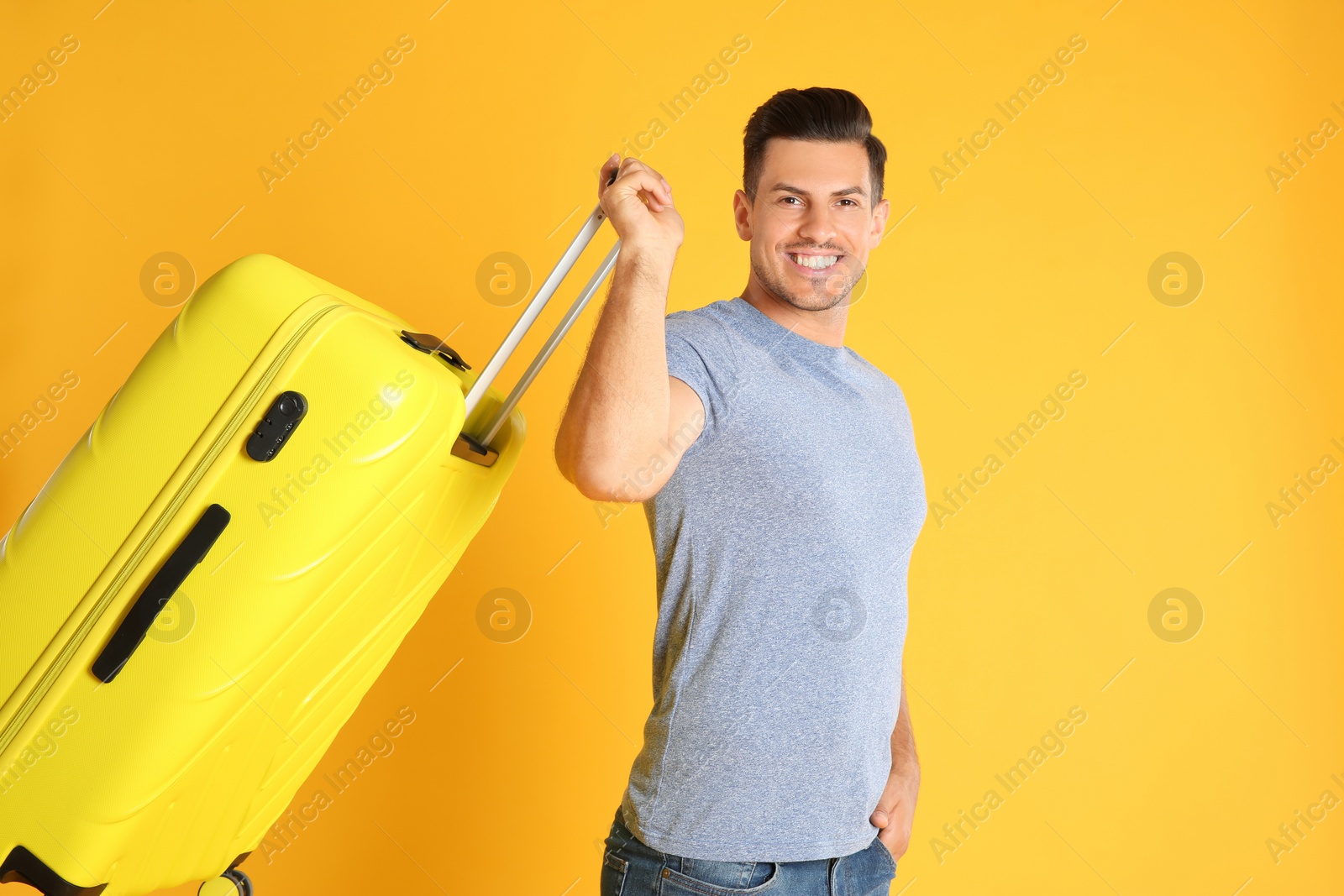 Photo of Handsome man with suitcase for summer trip on yellow background. Vacation travel