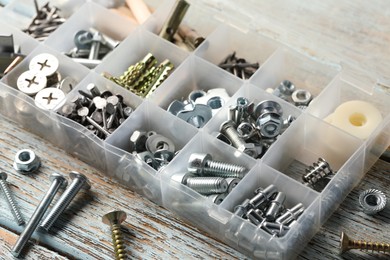 Photo of Organizer with many different fasteners on rustic wooden table, closeup
