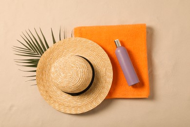 Photo of Beach towel, hat, sunscreen and palm leaf on sand, flat lay