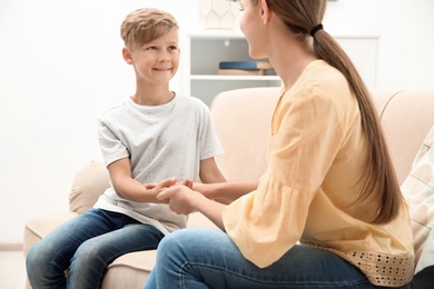 Young woman checking little boy's pulse indoors