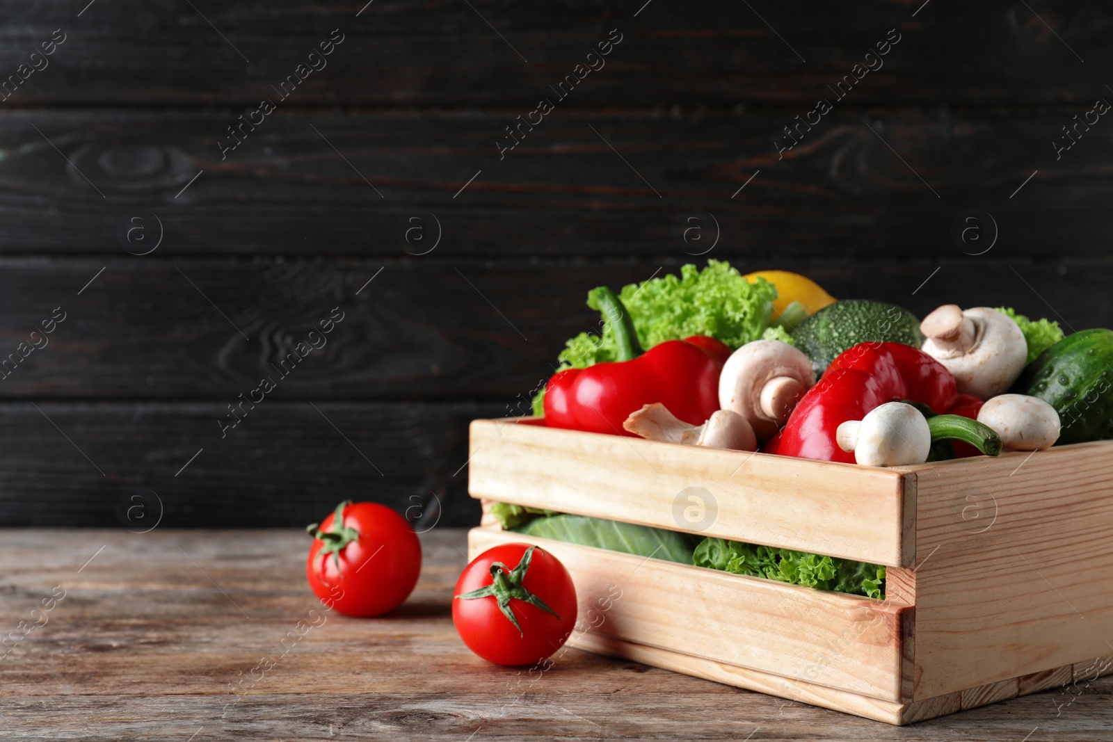 Photo of Wooden crate full of fresh ripe vegetables on table. Space for text