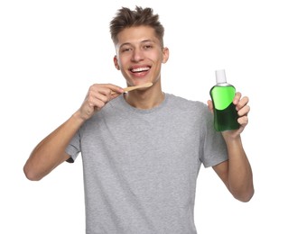 Young man with mouthwash and toothbrush on white background