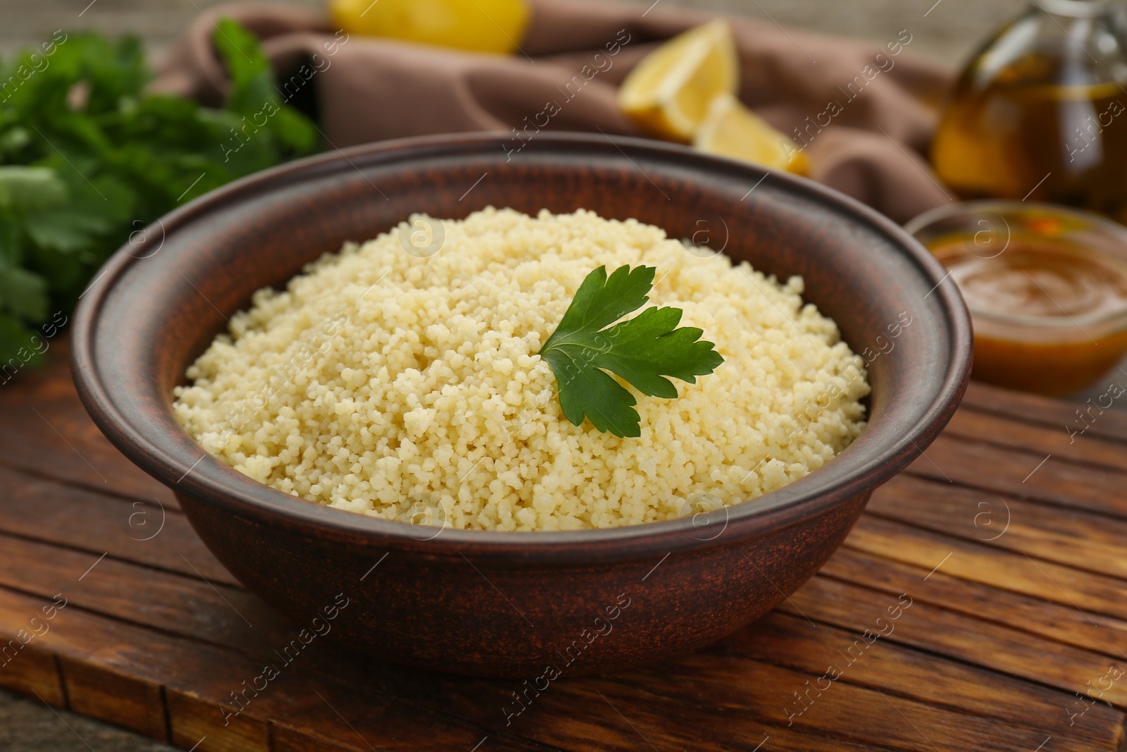 Photo of Tasty couscous with parsley on wooden board, closeup
