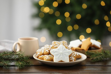 Decorated cookies and hot drink on wooden against blurred Christmas lights