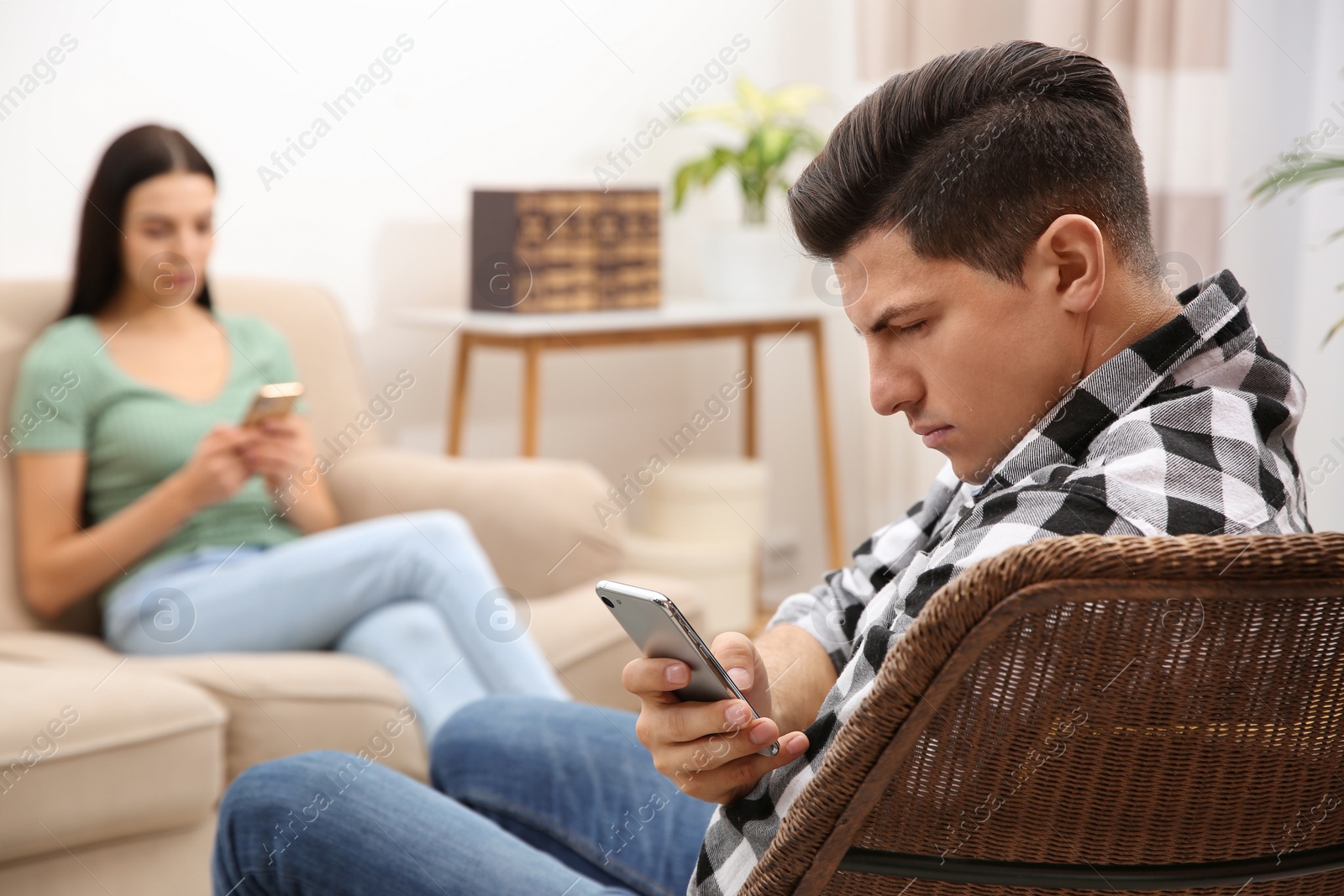 Photo of Couple addicted to smartphones ignoring each other at home. Relationship problems