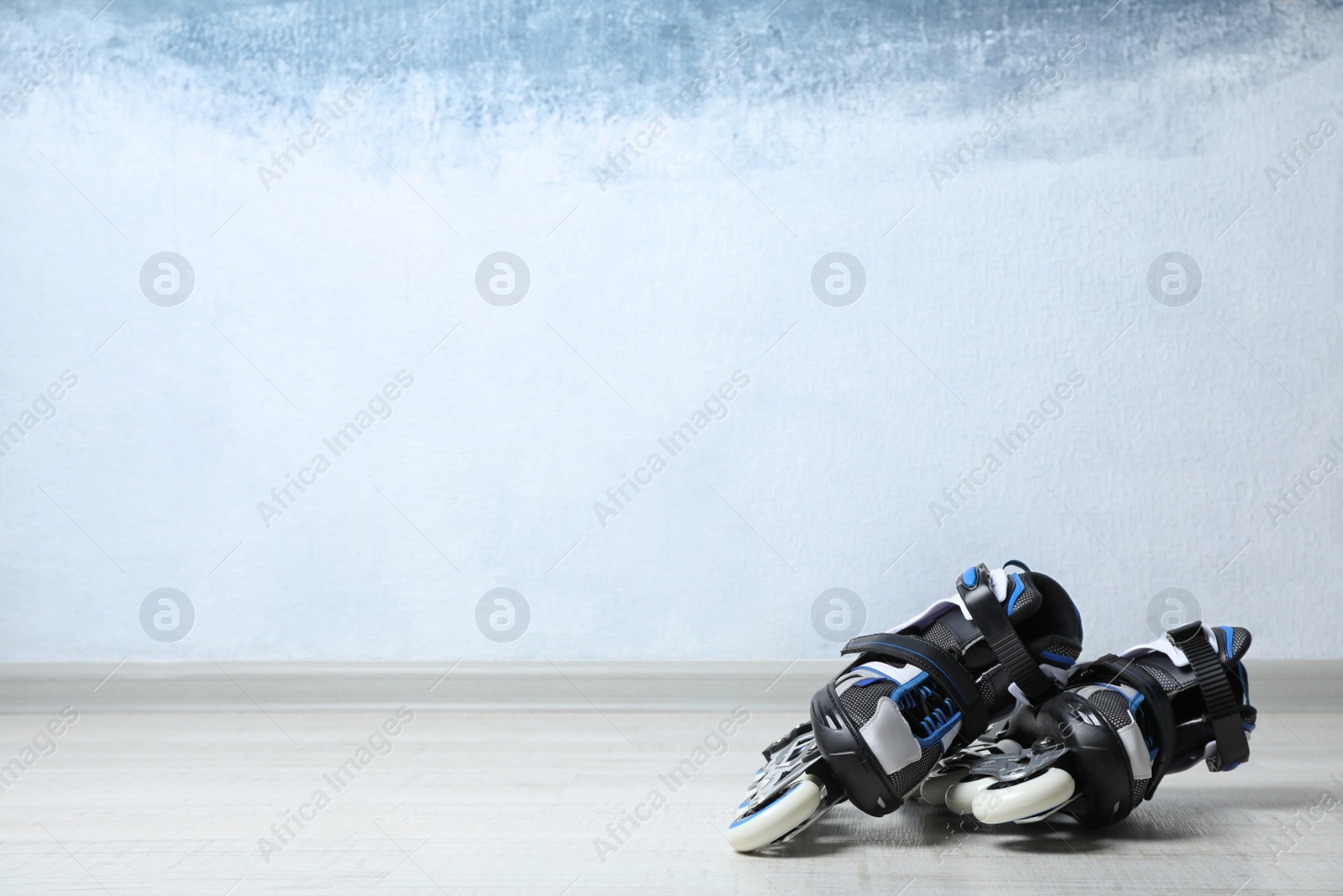 Photo of Inline roller skates on floor near color wall. Space for text