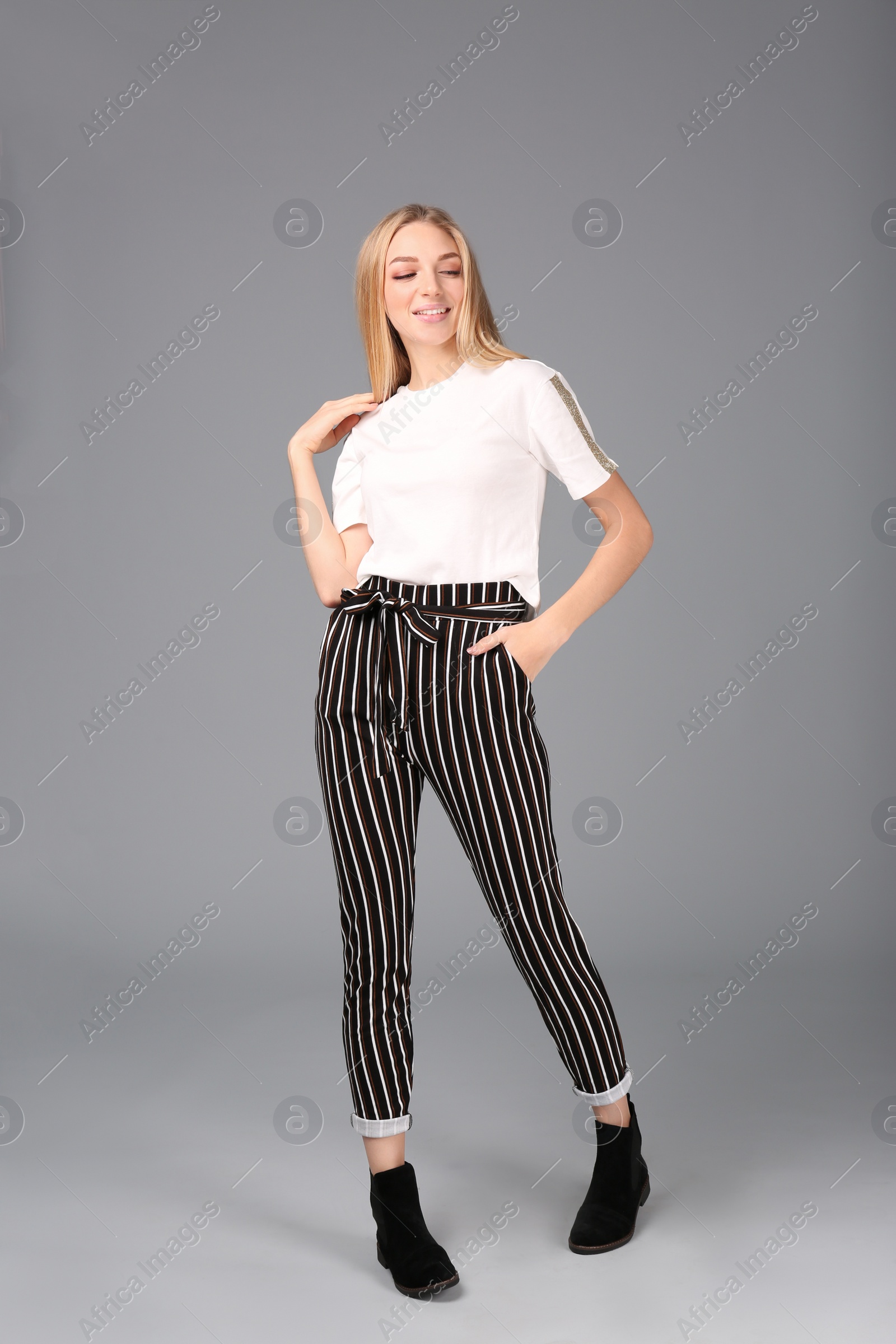 Photo of Young stylish woman in trendy shoes on grey background
