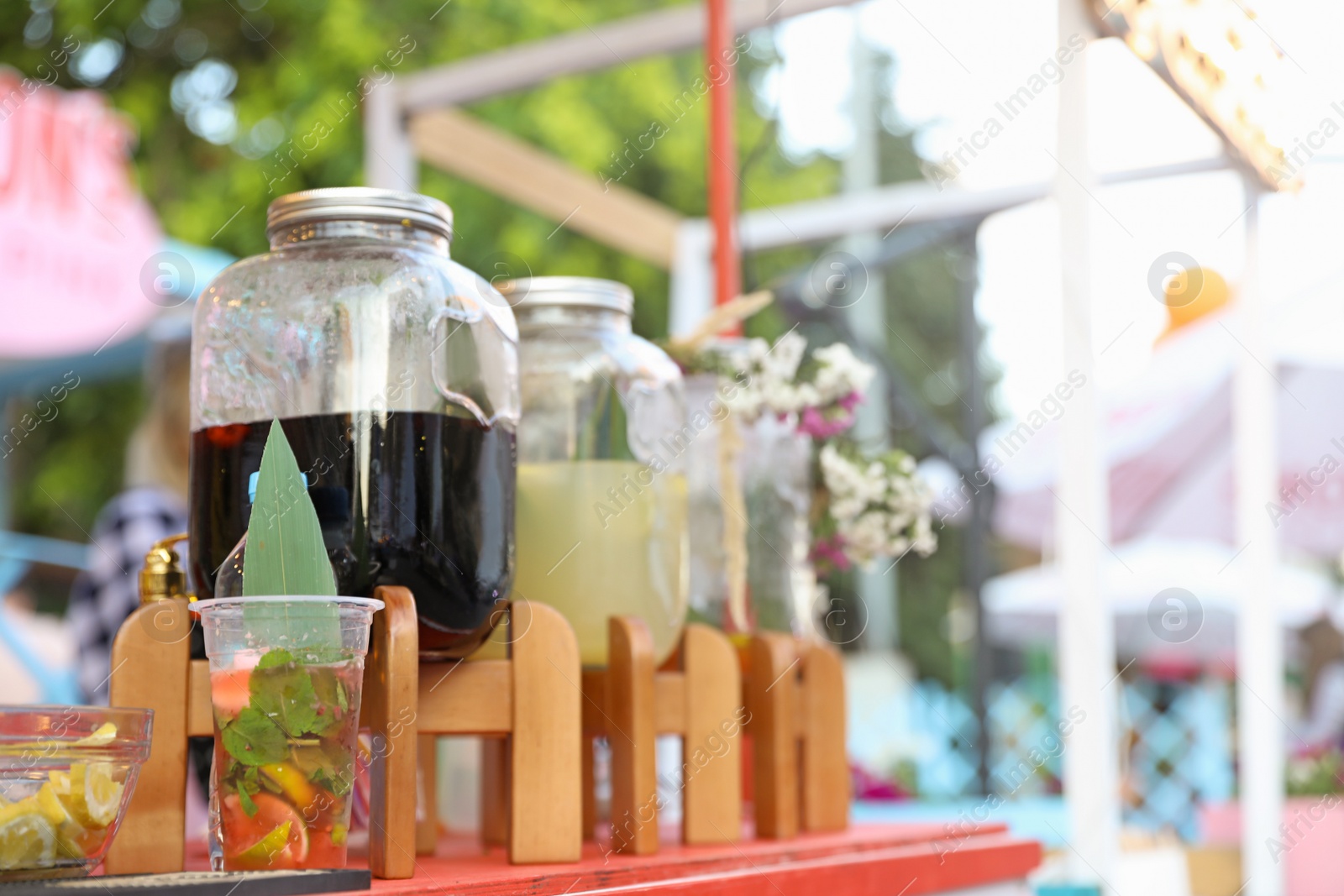 Photo of Glass jars with refreshing drinks on table outdoors