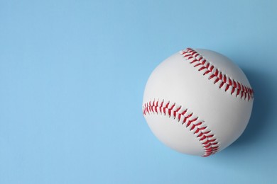 Photo of One baseball ball on light blue background, top view. Space for text