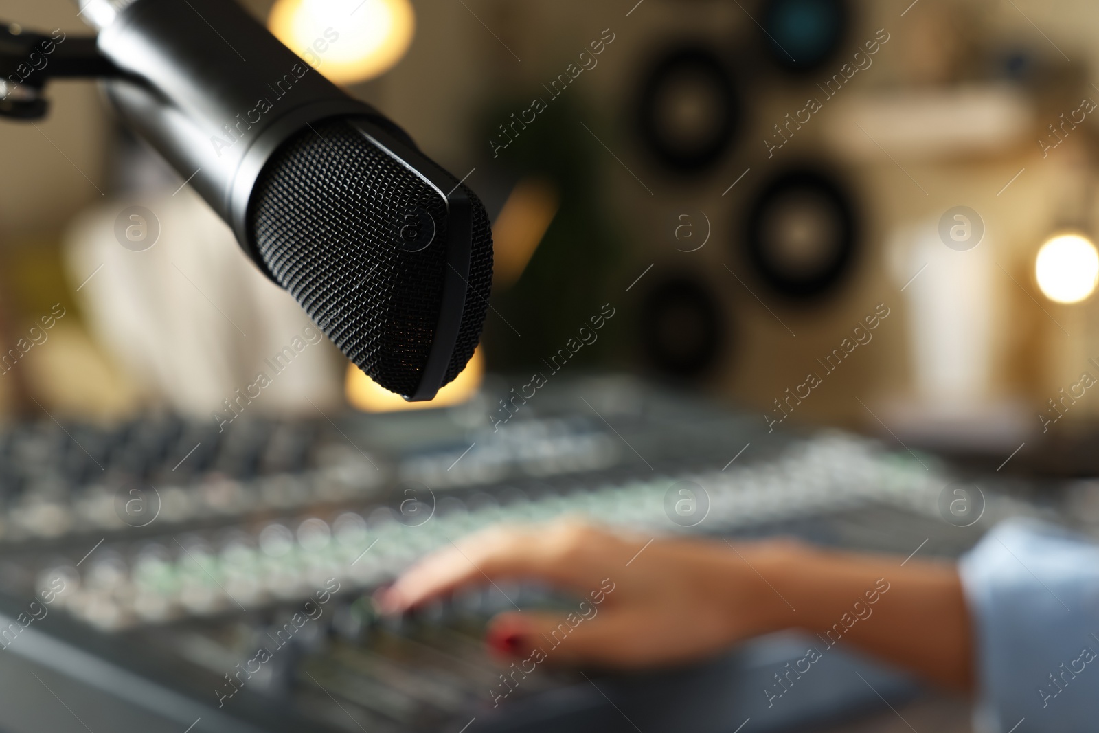 Photo of Woman working with professional mixing console in modern radio studio, focus on microphone. Space for text