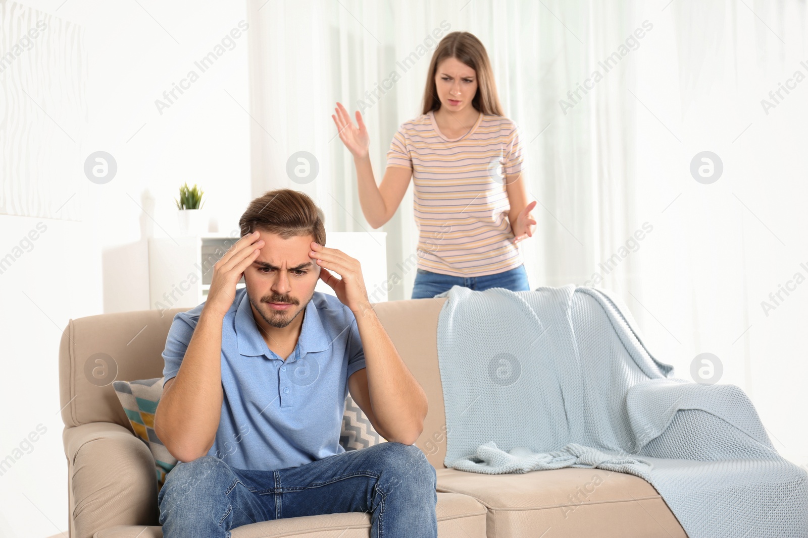 Photo of Young couple arguing in living room. Relationship problems