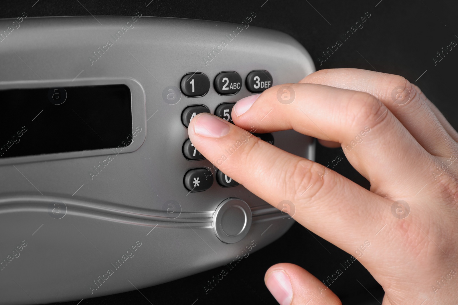 Photo of Man opening black steel safe with electronic lock, closeup