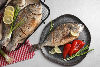 Seafood. Delicious baked fish served with green onion, bell pepper and lemon on light textured table, flat lay