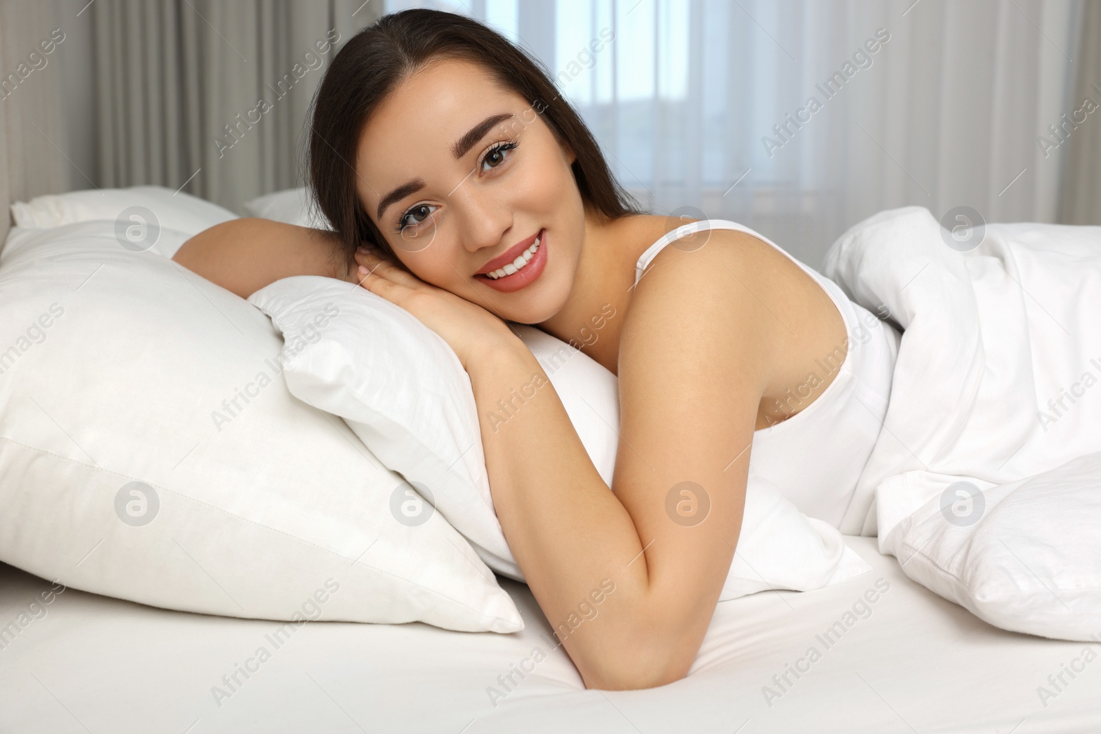 Photo of Beautiful young woman lying in bed at home