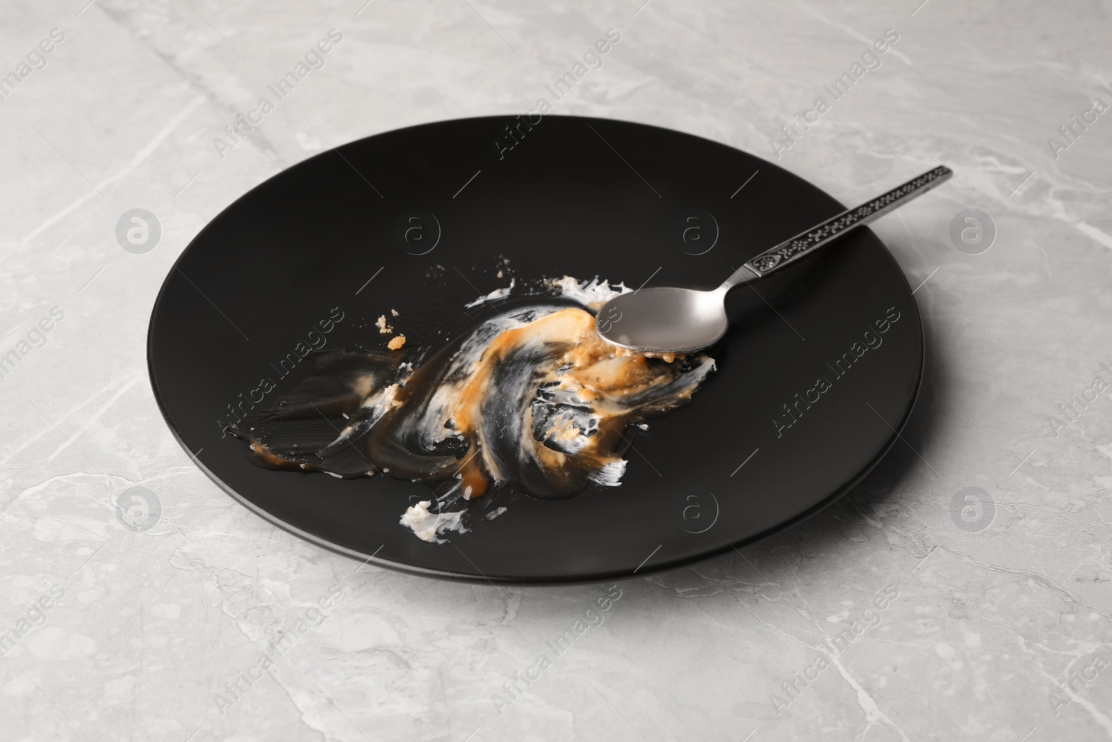 Photo of Dirty plate and spoon on light grey marble table