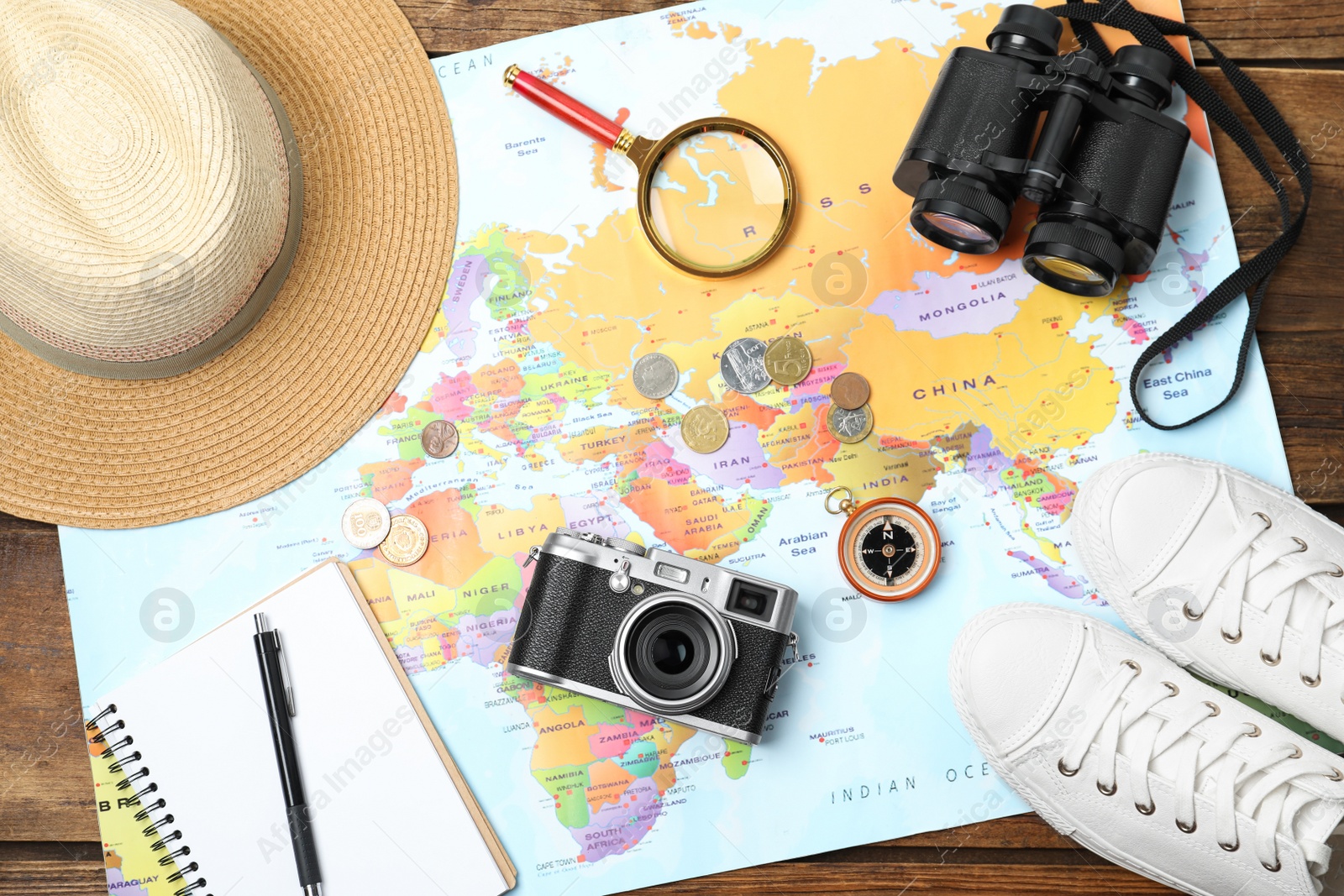 Photo of Flat lay composition with world map and different travel accessories on wooden table. Planning summer vacation trip