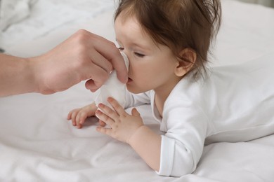 Father taking care of little baby suffering from runny nose in bed, closeup