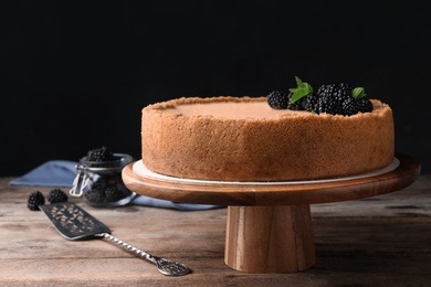 Photo of Delicious cheesecake decorated with blackberries on table