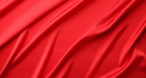 Crumpled red silk fabric as background, top view