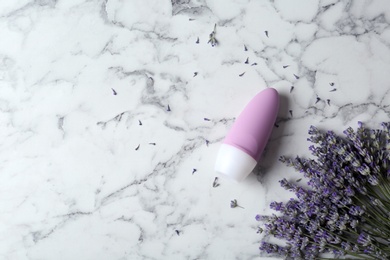 Female deodorant and lavender flowers on white marble background, flat lay. Space for text