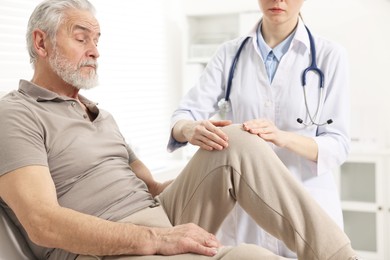 Arthritis symptoms. Doctor examining patient with knee pain in hospital