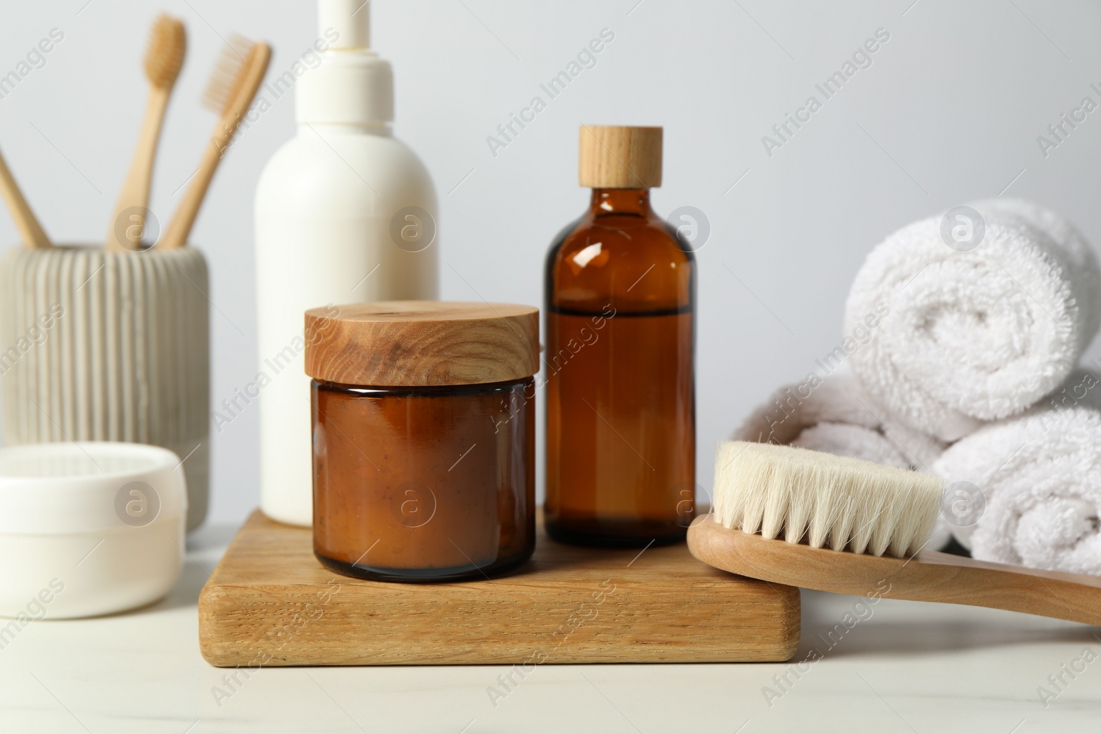 Photo of Different bath accessories and personal care products on light table against white wall