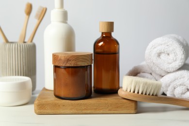 Different bath accessories and personal care products on light table against white wall