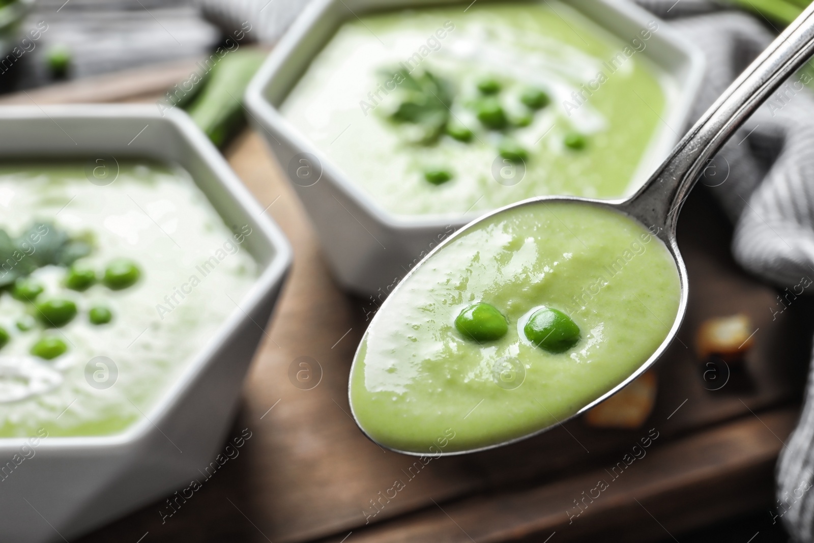 Photo of Spoon with fresh vegetable detox soup made of green peas on blurred background, closeup