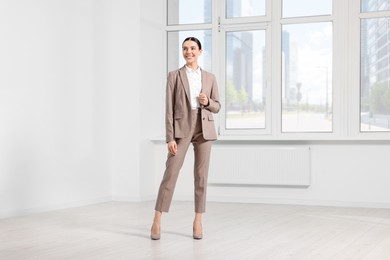 Photo of Beautiful real estate agent wearing nice suit in empty room