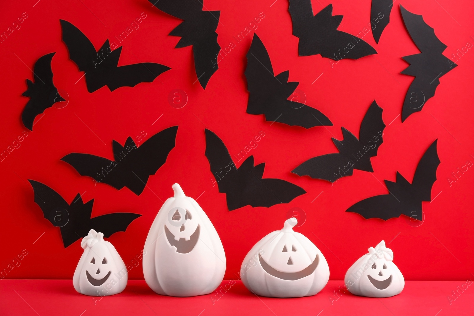 Photo of Composition with pumpkin shaped candle holders on red background. Halloween decoration