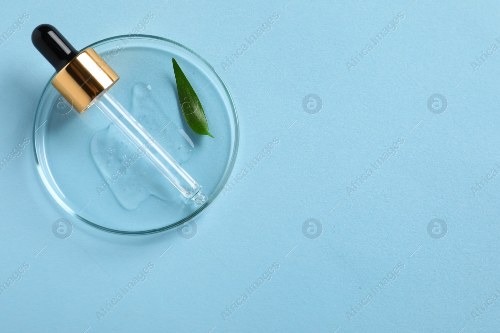 Photo of Petri dish with sample of cosmetic oil, pipette and green leaf on light blue background, top view. Space for text