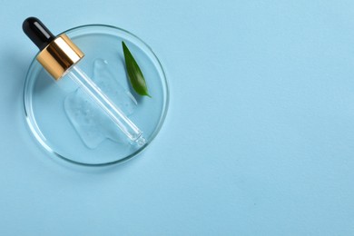 Petri dish with sample of cosmetic oil, pipette and green leaf on light blue background, top view. Space for text