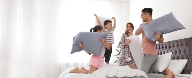 Image of Happy family having pillow fight in bedroom, space for text. Banner design