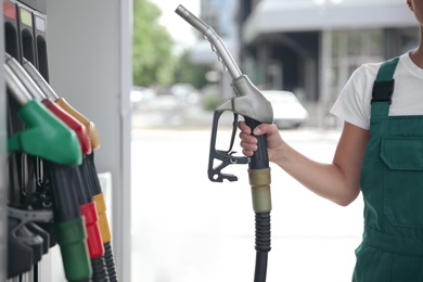Photo of Young worker with fuel pump nozzle at modern gas station, closeup