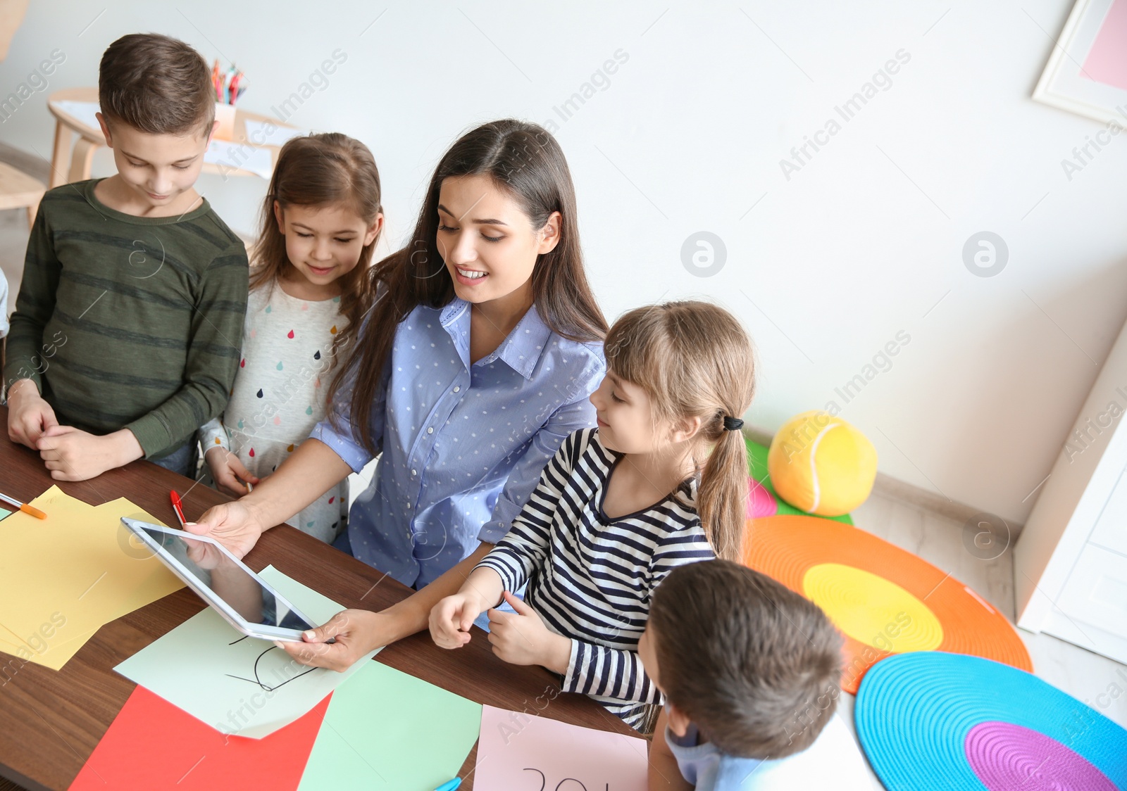 Photo of Cute little children with teacher in classroom at school