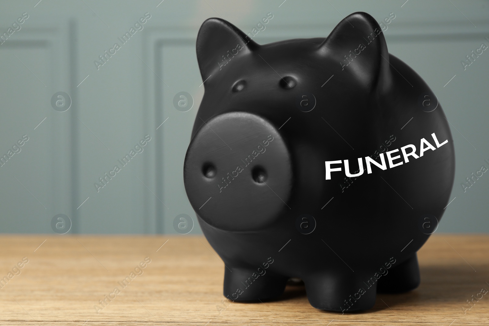 Image of Money for funeral expenses. Black piggy bank on wooden table. Space for text