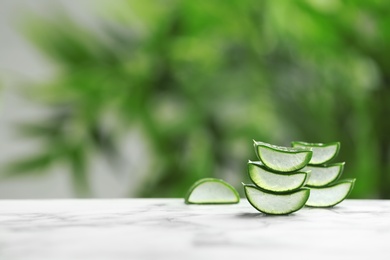 Photo of Slices of aloe vera on table against blurred background. Space for text